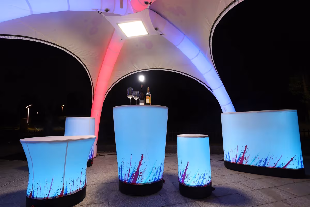 Dome-Zelt innen bei Nacht mit Leuchttischen unter farbig beleuchteten Luftbögen