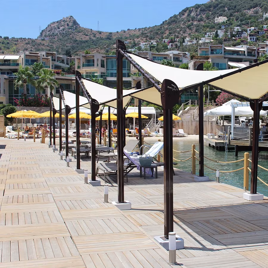 Reihe von Butterfly Pavillons mit cremefarbenem Gewebe an einer Strandpromenade