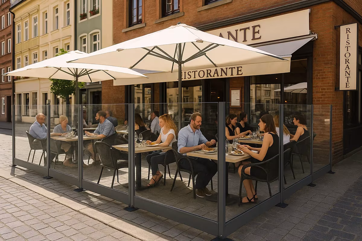 Glas-Windschutz an einer Restaurantterrasse mit Gästen unter Sonnenschirmen